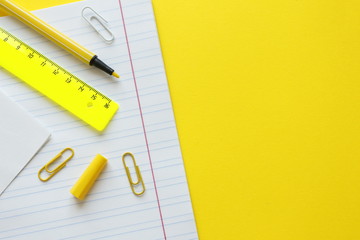 School supplies on yellow background. Back to school concept with space for text. Top view. Copy space. School office supplies.Creative desk with colourful stationery. Colored paper clip.