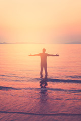 Fototapeta premium Freedom adventure and summer holiday concept. Happy man hand raise up standing on sunset beach and smooth wave abstract background.