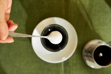 Spoon of sugar over coffee cup