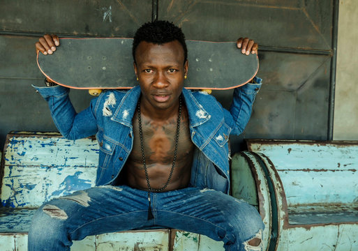 young attractive and fit black afro American man sitting on corner street bench holding skate board posing in cool attitude in youth urban style and city lifestyle