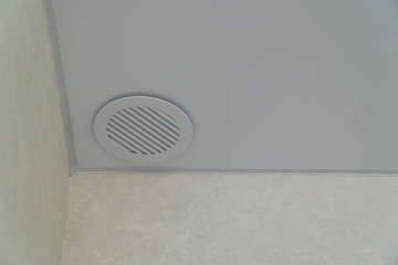 Round air-conditioning outlet on white ceiling