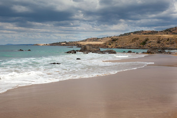 A storm is approaching and the beautiful secluded beach is seeing the last fading patches of sunlight.