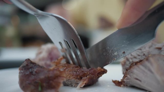 Closeup of grilled meat, skewers with various sauces. Cutting meat with a knife and fork