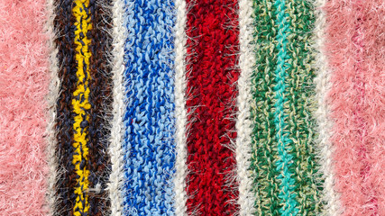 Obraz premium different colored stripes on the knitted fabric surface. background close-up of textiles retro rugs or rugs. the texture of the fabric is a combination with the geometry of the lines. handmade product