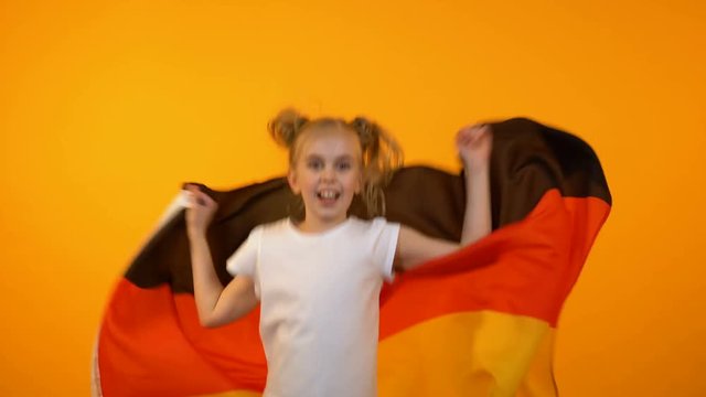 Adorable preteen girl jumping with german flag cheering for favorite sport team