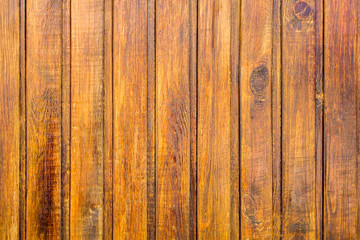 yellow brown fence wall of wooden planks closeup. vertical lines. rough surface texture