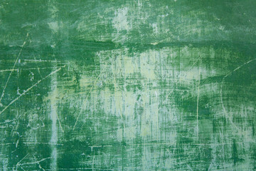 old shabby green wall with white spots, scratches and cracks. rough surface texture
