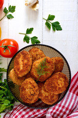 Juicy homemade cutlets (beef, pork, chicken) on a white wooden background.