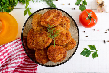 Juicy homemade cutlets (beef, pork, chicken) on a white wooden background.