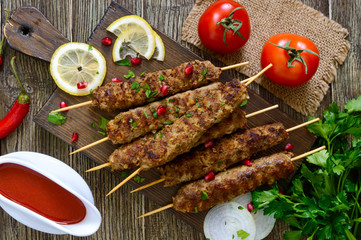 Delicious lula kebab on a wooden table. Chopped meat on wooden skewers, grilled. Eastern cuisine. Top view, flat lay.