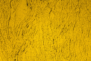 a bright yellow wall with undulating lines and deep relief with shadows and black dots. rough surface texture