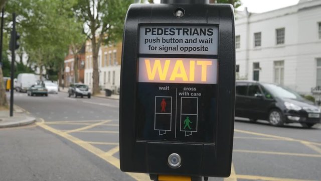 Pedestrian lights sign by a busy road in a city.