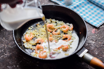 Shrimp frying in a milk sauce in a pan.