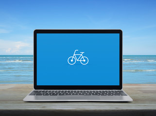 Bicycle flat icon with modern laptop computer on wooden table over tropical sea and blue sky with white clouds, Business bicycle shop online concept