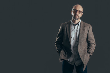 Fototapeta premium Serious middle aged man with a deadpan face expression dressed in casual posing on a dark gray background