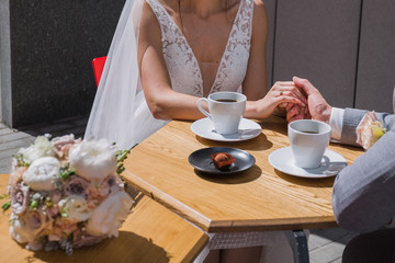 the bride and groom sit at a table in a cafe drinking coffee