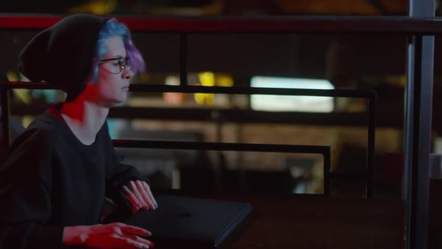 Tracking left of young woman-hipster putting laptop on table in bar and starting typing on keyboard