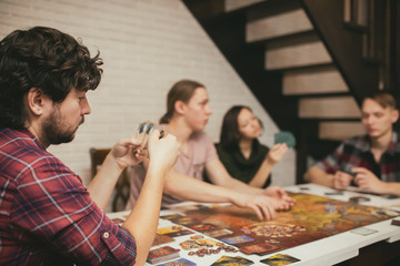 Group of friends sitting at the table. Young People having fun while playing board game.