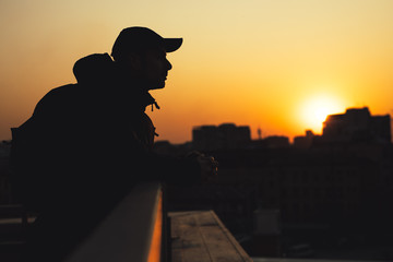 Dreaming man silhouette in a city sunset looks around