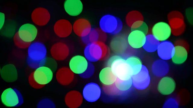 Abstract background of christmas lights. Smooth movement. Shaking from the wind. Flickering colored lights on a dark background. Defocused image. Colorful Christmas lights