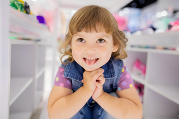 Adorable smiling happy little girl at the clothes store