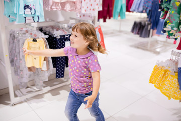 Adorable smiling happy little girl at the clothes store