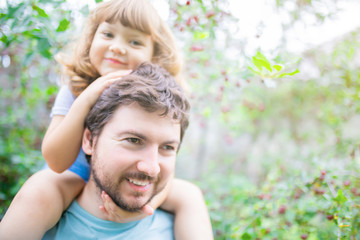 Young father and his toddler girl, riding on his shoulders