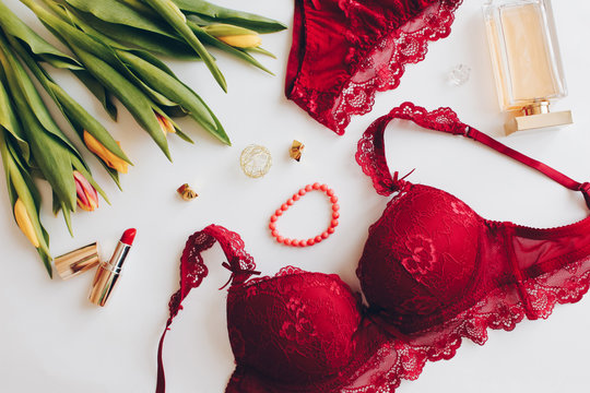 Red women underwear and spring Tulips flowers on white. Red bra and pantie. Copy space. Beauty, fashion blogger concept. Romantic lingerie for Valentine's day temptation.Erotic concept.Floral pattern.