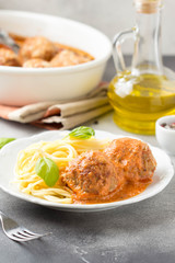 Meatballs in tomato sauce with cheese and pasta spaghetti, baked pork and beef cutlets in baking dish. Delicious homemade food