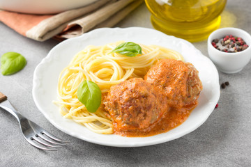 Meatballs in tomato sauce with cheese and pasta spaghetti, baked pork and beef cutlets in baking dish. Delicious homemade food