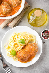 Meatballs in tomato sauce with cheese and pasta spaghetti, baked pork and beef cutlets in baking dish. Delicious homemade food