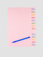 The pink sheet of paper pinned with colored paper clips, on white, with a ballpoint pen, for background, isolated on white
