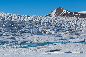 surface of Esmarkbreen glacier in Svalbard in sunshine, blue sky
