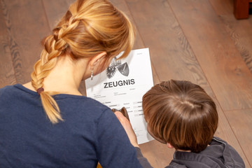 Mother holding a very bad German school certificate in her hands Translation: certificate day of...