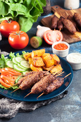 Grilled shish kebab served with fried potatoes