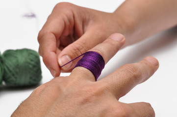Obraz premium Man's hand and purple yarn isolated on a white background.Crochet.