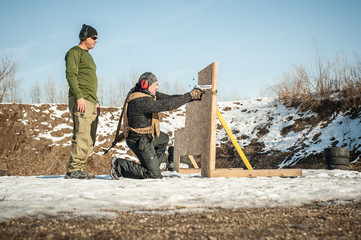 Instructor teaches student tactical gun shooting behind cover or barricade