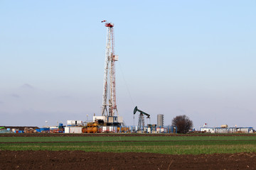 land oil and gas drilling rig and pump jack in oilfield