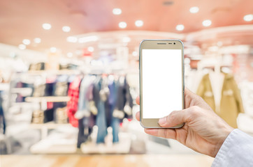 Mockup image of man hand holding gold mobile phone with blank white screen on blurred abstract background of many cotton clothing on the shelves of fashion shop.business concept.shopping online.