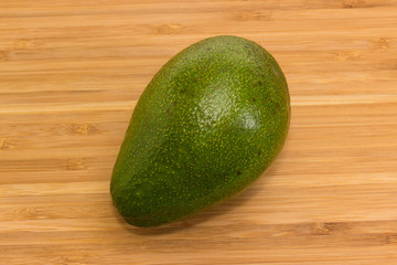 Whole green avocado fruit on a wooden surface