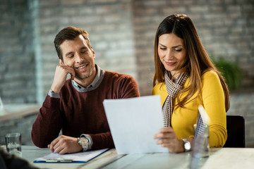Smiling couple analyzing their financial reports together in the office.