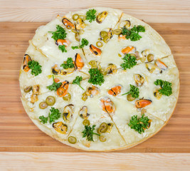 Cooked round pizza with mussels on the bamboo cutting board