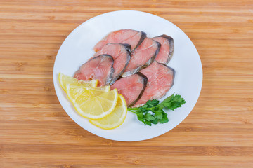 Slices of smoked pink salmon, lemon and parsley on dish