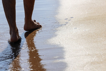 Close up on moving feet of a man walking on the beach in the afternoon at Koh Mak in Trat, Thailand.