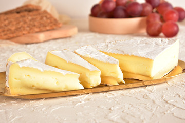 Fresh brie cheese on a golden saucer. Grapes, honey and olives. Top view.