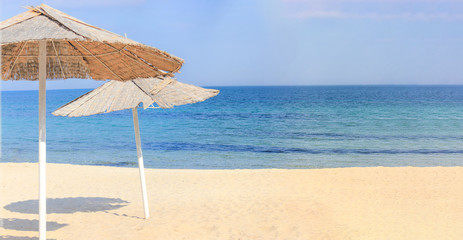 Beach umbrellas and clean sand against the backdrop of the azure coast of the sea. Vacation and Tourism concept.