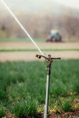 Irrigation plant system on a field, agriculture. Tractor in the blurry background.