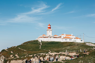 Fototapeta na wymiar Scenic view of the lighthouse at Cape Roca in Sintra in Portugal. Nearby unrecognizable people or tourists look at the sights.