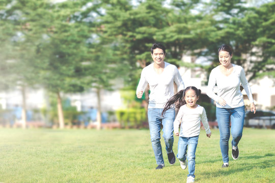 Young Attractive Happy Asian Family Playing By Running Together In Outside Nature Park In Home School Learning Or Montessori Concept With White And Blue Casual Wearing. Asian Lifestyle Parenting.