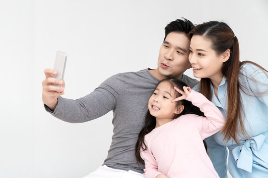 Candid of young attractive happy asian family using smartphone selfie together or video call. Social media community in asian family using 5G digital technology conference to connected people concept.